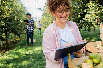 Portrait of young female farmer working in pears orchard.