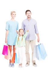 Studio portrait of father, mother and their daughter standing together holding shopping bags, girl pointing finger at something, white background