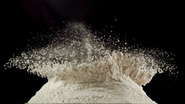 Super slow motion in a pile of flour on the table drops raw egg. On a black background.Filmed on a high-speed camera at 1000 fps.