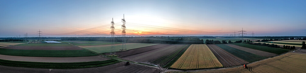 Panoramic image of power line over land during sunset in afterglow