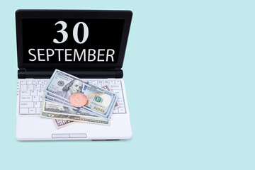 Laptop with the date of 30 september and cryptocurrency Bitcoin, dollars on a blue background. Buy or sell cryptocurrency. Stock market concept.