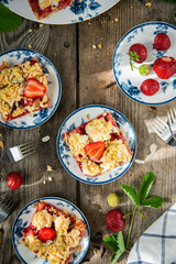 Strawberry and rhubarb meringue crumble squares on white and blue plates on wooden table.