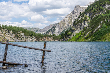 The idyllic Tappenkar Lake in the Austria Alps with a wooden fence reaching into the water