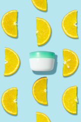 Creative beauty fashion concept photo of cosmetic recyclable bottle lotion cream with oranges on blue background.