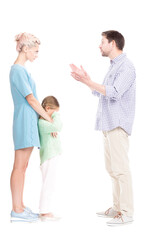 Vertical full length side view studio shot of husband and wife having conflict quarrelling, their daughter feeling sad about it, white background
