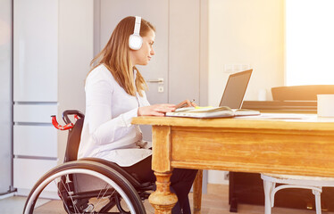 Behinderte Frau im Rollstuhl arbeitet am Computer zu Hause