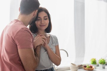 young brunette couple gently holding hands in kitchen