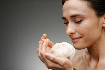 Close up of a mid aged brunette woman holding peony bud © Drobot Dean