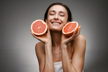 Smiling healthy mid aged topless woman holding grapefruit