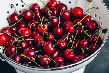 Cherry. Sweet Cherries in white colander on dark stone concrete background. Ripe Sweet Red Cherries.