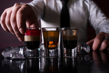 Barman preparing cocktail shots at the bar counter. Barman mixing drinks at the night club..