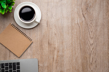 Flat lay, top view office table desk. Workspace with, laptop,office supplies, pencil, green leaf, and coffee cup on wood background.