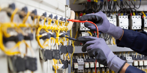 Electrician engineer tests electrical installations and wires on relay protection system. Adjustment of scheme of automation and control of electrical equipment.