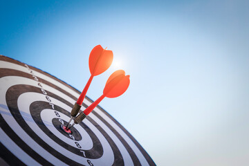 Close up shot red darts arrows in the target  of dartboard center on dark blue sky background. Business target or goal success and winner concept.