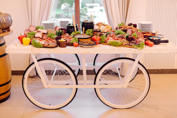 Traditional national meat buffet decorated in form of cart with large wheels in rural hotel. Recreation and tourism. Registration of weddings and events. Decor of restaurant.