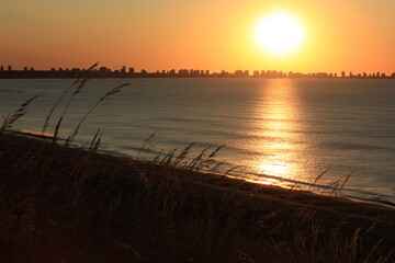 Hermoso amanecer con reflejo del sol en el mar y silueta de la ciudad