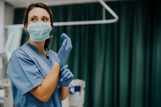 Female Nurse With A Mask Putting On Gloves