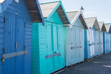 Fototapeta na wymiar Line of blue and green painted wooden beach huts