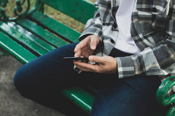 teen boy using smartphone device for online network technology internet;  man use mobile in public park