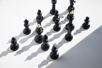 chess, black figures on a light table surface, indoors. Intellectual games for children and adults, logic, thinking, chess on the table, in the shade