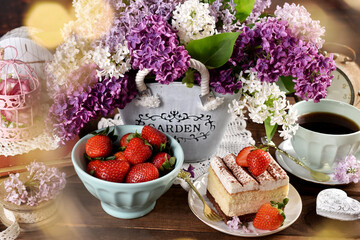 cream cake with strawberry and fresh fruits on rustic table with lilac flowers