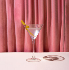 A glass of cocktail, martini in front of reach pink renaissance velvet curtain. Retro style theatre vibe. - obrazy, fototapety, plakaty