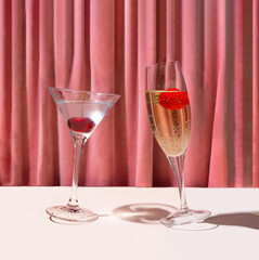 A glass of cocktail and a glass of champagne in front of reach pink renaissance velvet curtain....