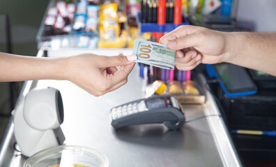 Young woman paying money in supermarket.