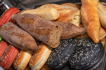 Hamburger buns of different colors and shapes on a metal tray with selective focus
