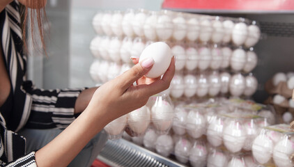 Caucasian woman buying eggs in supermarket.