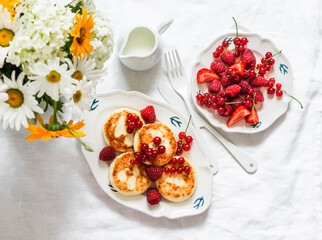 Syrniki with red currant, raspberry and sour cream on the light   background, top view. Delicious breakfast, brunch
