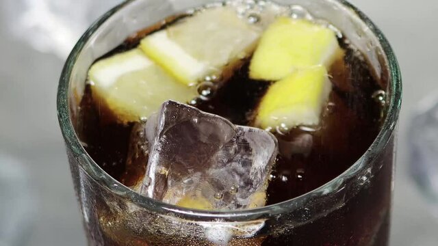 Frisches k&uuml;hles Kohlens&auml;urehaltiges Softgetr&auml;nk Getr&auml;nk ins Glas mit Eisw&uuml;rfel und Zitronenschnitz giessen