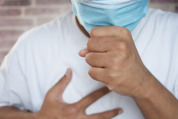  young sick man in face mask coughing and sneezes 