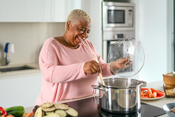 Happy senior woman preparing lunch in modern kitchen - Hispanic Mother cooking for the family at home - 442330125