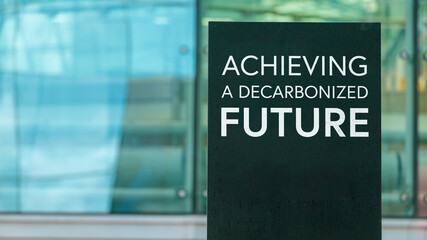Achieving a decarbonised future  on a city-center sign in front of a modern office building	
