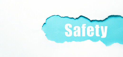 safety word under torn white paper on blue.