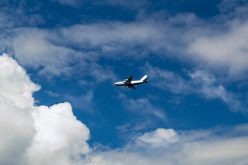 Aerial concept on a blue sky among white clouds and sunlight a passenger or cargo plane is flying