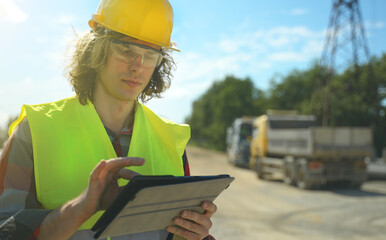 Builder with tablet pc at road junction construction site.
