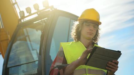 Excavator operator in hard hat using tablet pc.