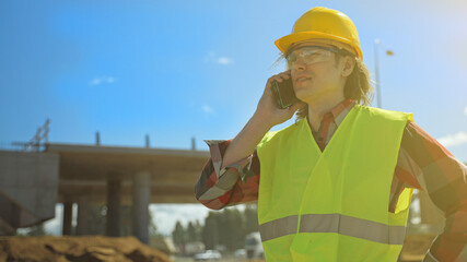 Builder talking by smartphone at construction site.