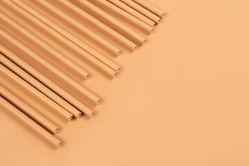 Close up view of eco-friendly paper drinking straws on light brown paper background with copy space. Sustainable paper packaging concept. Selective focus