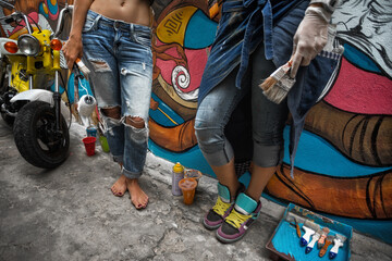 Obraz premium Street art. Cheerful young women painting on the wall. Street art.