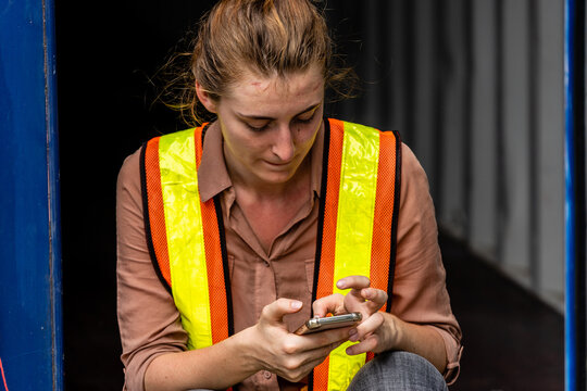 Caucasian worker sitting in container box and using smart phone when his break