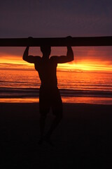 Silueta de hombre musculoso hace ejercicio en la playa al atardecer - obrazy, fototapety, plakaty