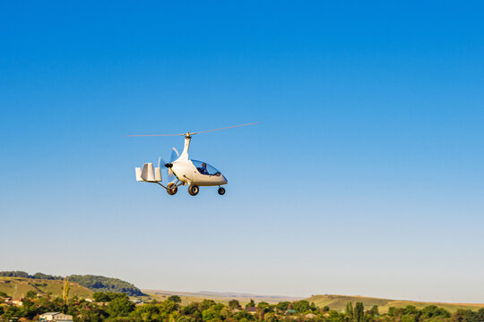 Autogyro Calidus taking off over an unpaved airfield.