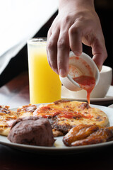 adding tomato sauce to a couple of pupusas

