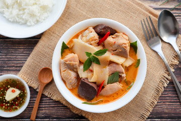 Thai red curry with chicken and bamboo shoot with rice and spicy fish sauce - Thai food called Kang Nor Mai at top view on wood table