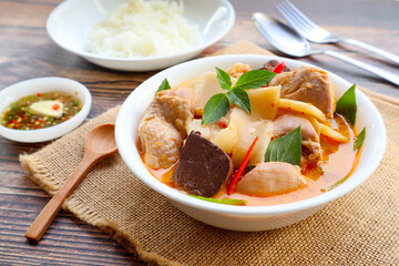 Thai red curry with chicken and bamboo shoot with rice and spicy fish sauce - Thai food called Kang Nor Mai at close up view on wood table