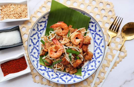 Stir fried turnip cake with shrimp, bean spout and chives - Thai -Chinese food called Kanom Pak kad or Char Koay Kak at top view on marble table