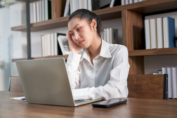 Stressed businesswoman sitting at desk working with laptop for online marketing in co-working space , Unhappy concept
